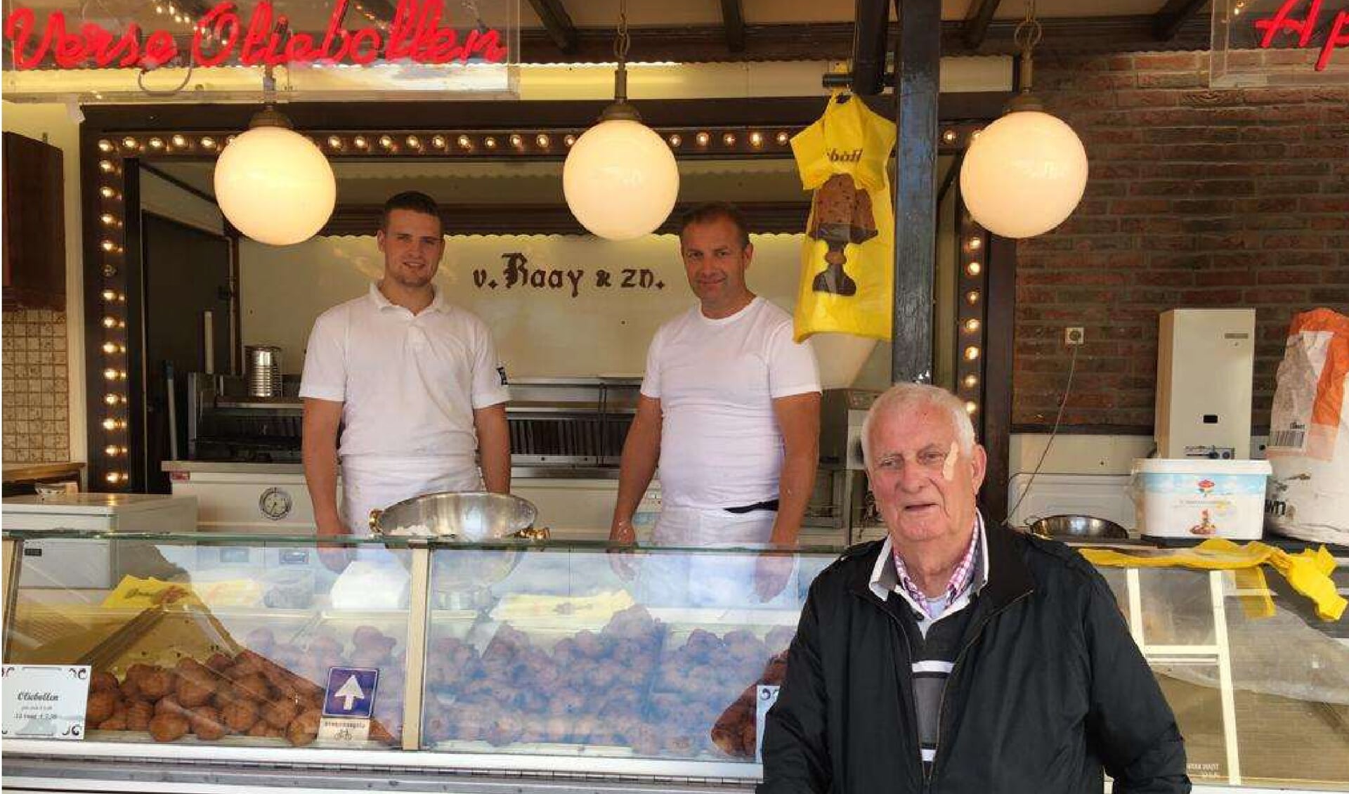 Marco van Raaij (r) in de kraam samen met zijn zoon Jory. Buiten staat vader Gerrit die ook vele jaren oliebollen en andere lekkernijen in Ruurlo verkocht. Foto: PR