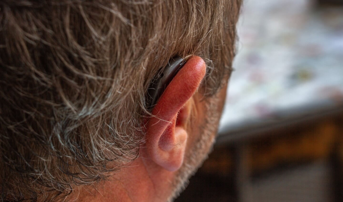 Een klein hoortoestel die gedeeltelijk in de gehoorgang gedragen wordt en deels buiten het oor. Foto: Liesbeth Spaansen