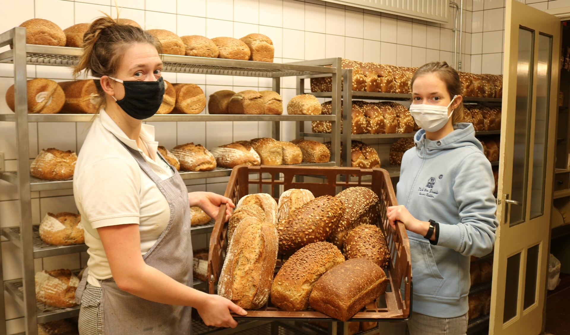Terwijl Anna (l) en Sara (r) druk in de bakkerij zijn, is hun vader Dick ten Broeke in de winkel het brood aan het verkopen. Foto: Arjen Dieperink