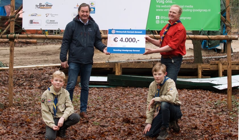 <p>Op de plek waar het nieuwe clubhuis komt overhandigt Joost Snoep (l.), voorzitter Rotary Gorssel, de cheque voor 4.000 euro aan enkele scouting jeugdleden en aan Niels Meijerink, voorzitter Scouting IJsselgroep Gorssel. Foto: PR</p>