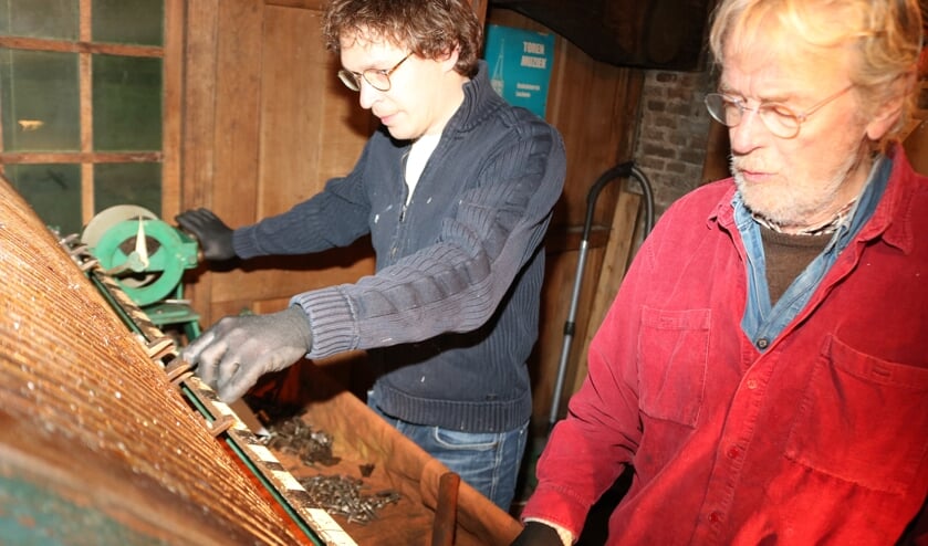 <p>Beiaardier Jan-Geert Heuvelman (links) en Frits Wits (rechts) zijn bezig de noten te plaatsen op de speeltrommel. Foto: Arjen Dieperink</p>