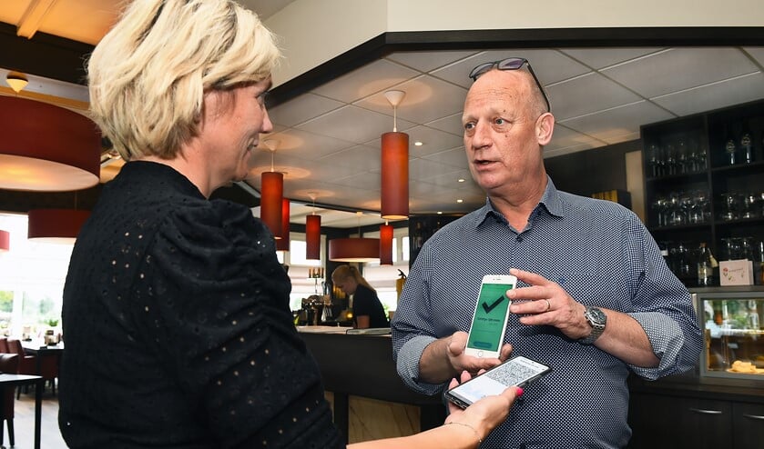 Carl Aalders van het Tolhuis scant een een corona-app. Foto: Roel Kleinpenning