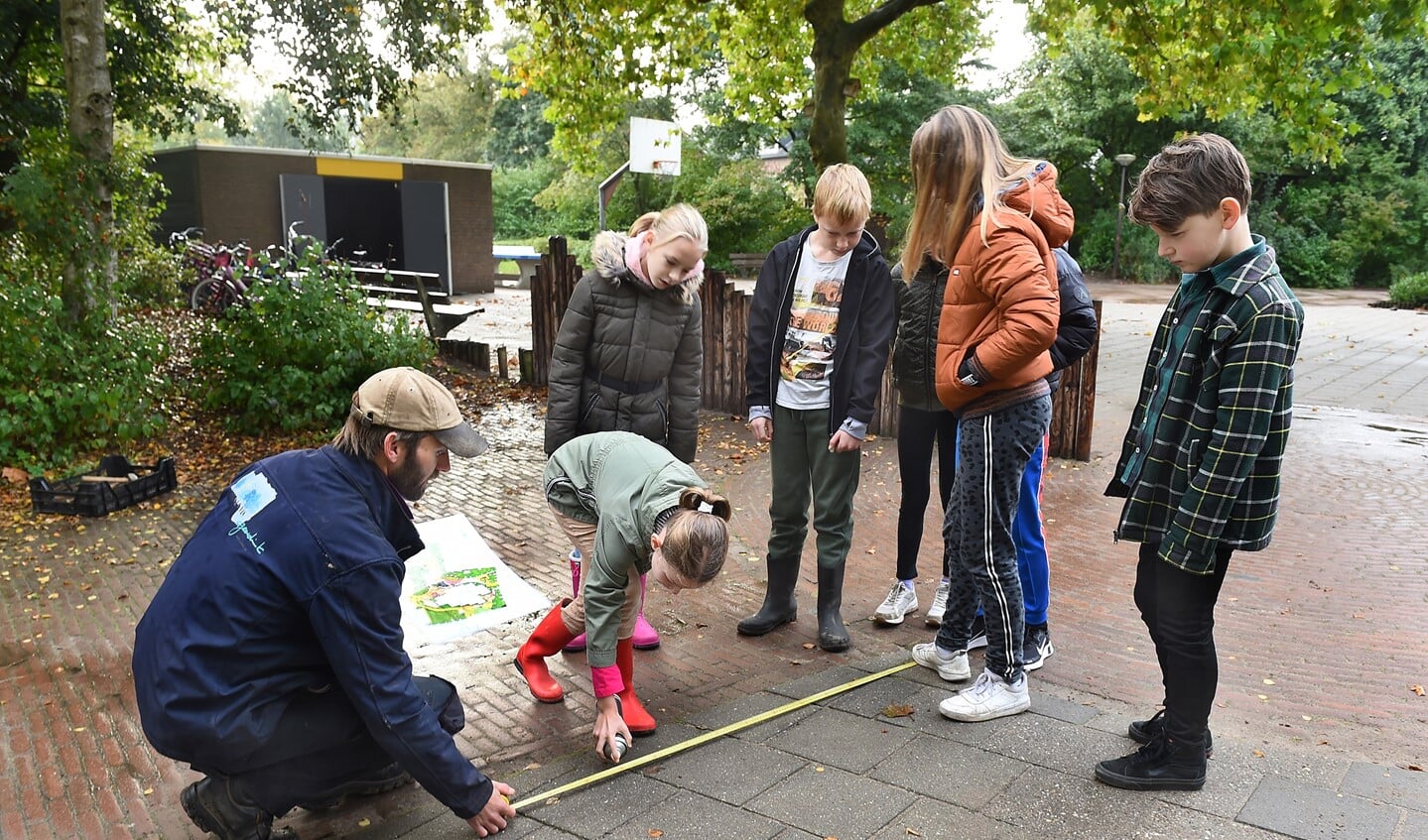 Robin de Wit (Geerdink Tuinen), met spuitbus Vera (leerling groep 6) van OBS Wis en Wierig Gaanderen. Foto: Roel Kleinpenning
