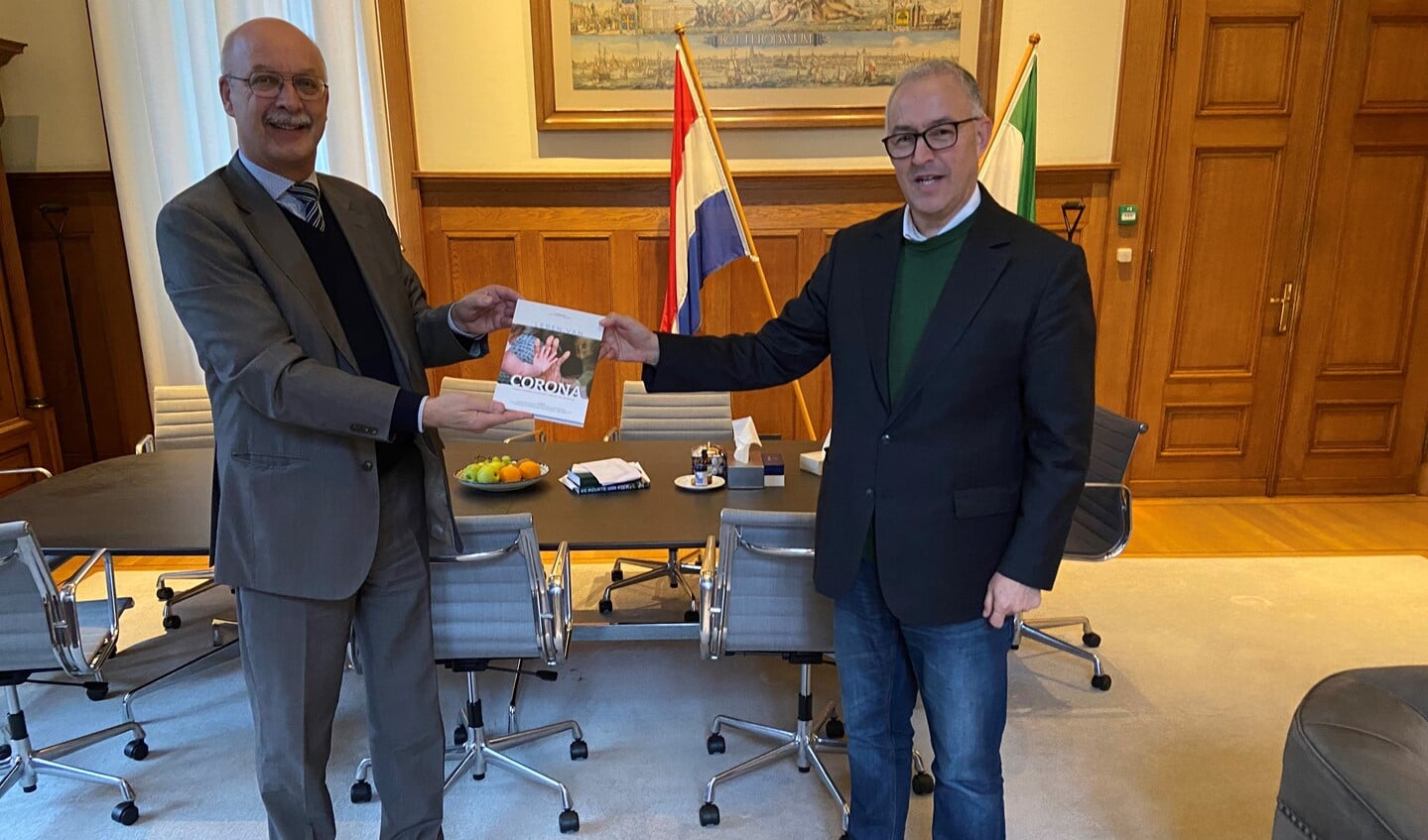 Crisisexpert Gert-Jan Ludden overhandigt het nieuwe boek 'Leren van corona - inspirerende inzichten vanuit de praktijk' aan de Rotterdamse burgemeester Ahmed Aboutaleb. Foto: Bas Eenhoorn