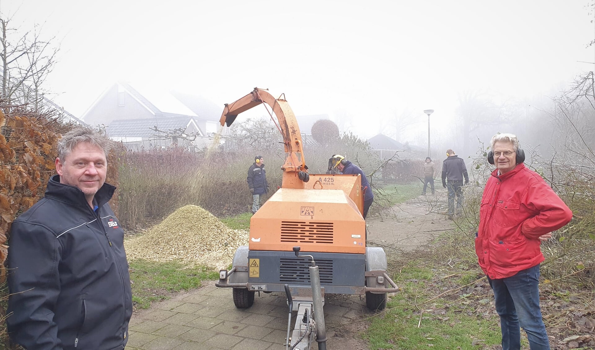 Arjen Heutinck (links) en Roel Beunk bij de op volle kracht draaiende houtversnipperaar. Foto: Henri Walterbos