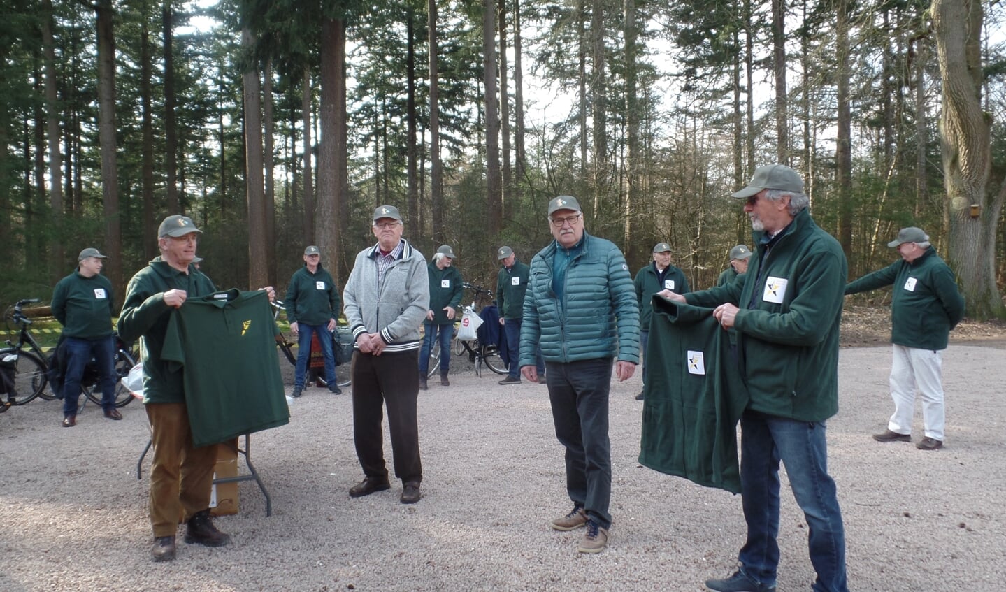 Uit handen van de bestuursleden Wim Slotboom (l) en René Swienink (r) krijgen de vrijwilligers van het doolhof een nieuwe outfit aangeboden. Foto: Jan Hendriksen 