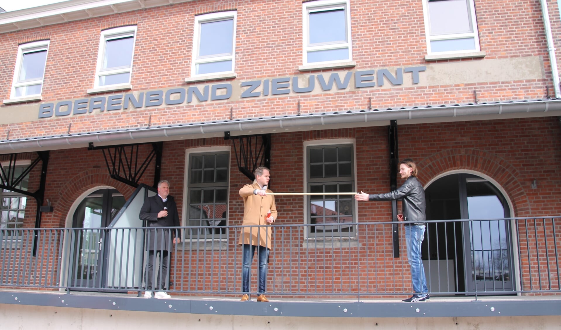 Stijn Papen ontvangt coronaproof de sleutel van zijn appartement uit handen van wethouder Porskamp. Links Sjaak Jansen (BondGenoten). Foto: Annekée Cuppers