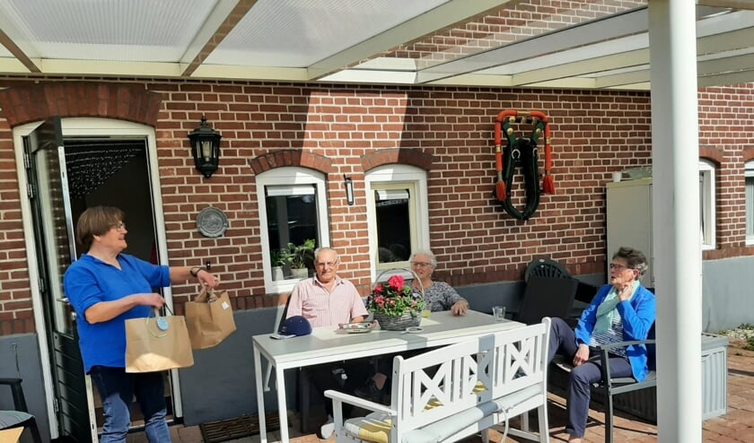 <p>Vrijwilliger Christien Kremer levert de verrassingsmenu's af bij het echtpaar Bussink, en hun gast mevrouw Lammers. Foto: H. Vriezen</p>