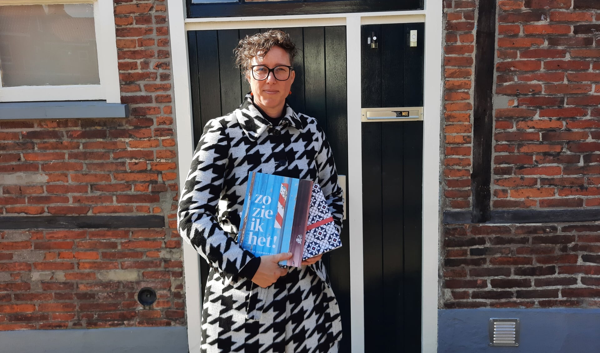 Linda Commandeur met haar nieuwste boek. Eén exemplaar is alvast verpakt in het nieuwe Grolse Wanten-inpakpier. Foto: Kyra Broshuis
