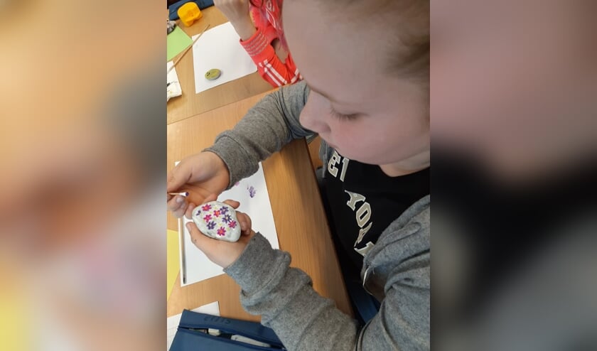 Een leerling versiert een zwerfkei voor iemand anders. Foto: Stefanie Klein Avinck