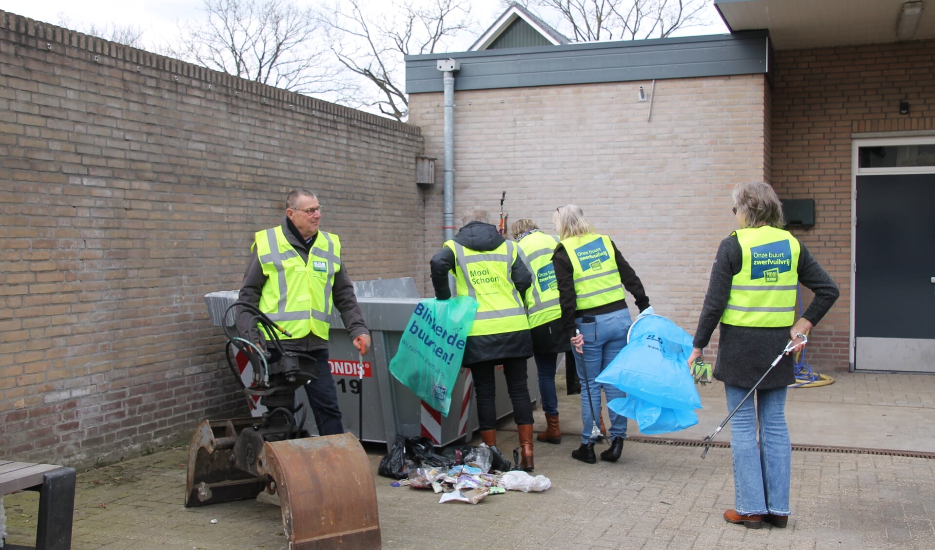 Gerard en een aantal leden van de groep Schoon Oost Gelre bij de afvalcontainer achter het gemeentehuis. Foto: Annekée Cuppers