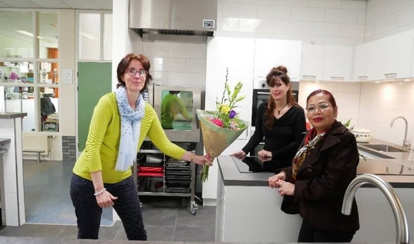 <p>Directeur-bestuurder Jorinde Klungers (Perspectief Zutphen) overhandigt bloemen aan vrijwilliger Nina Lalenoh en sociaal beheerder Greet Zweers in de nieuwe keuken van buurthuis De Uitwijk. Foto: PR</p>