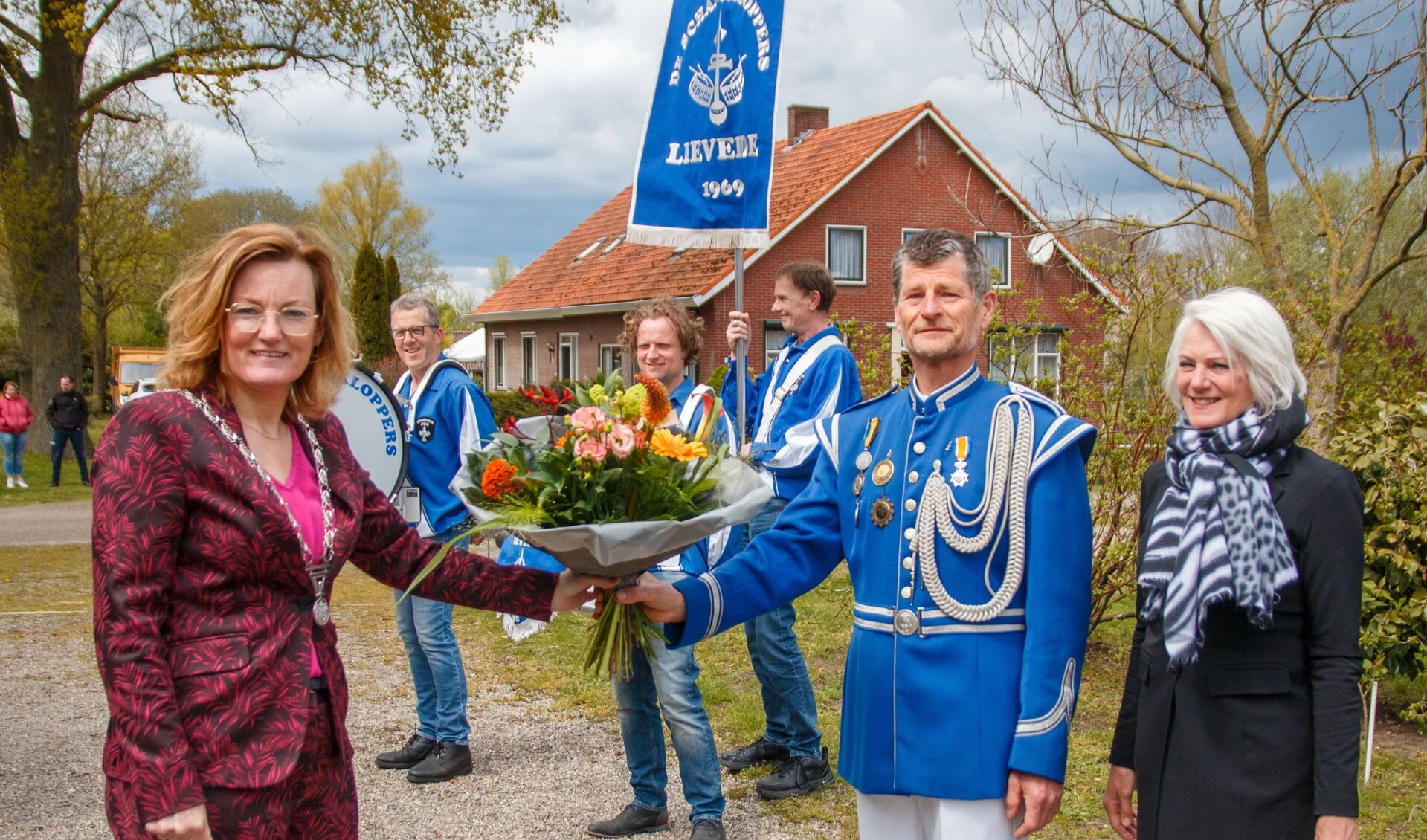 Locoburgemeester Marieke Frank reikt een koninklijke onderscheiding en bloemen uit aan Broddy Krabbenborg. Rechts zijn vrouw, Nardy Krabbenborg. Foto: PR