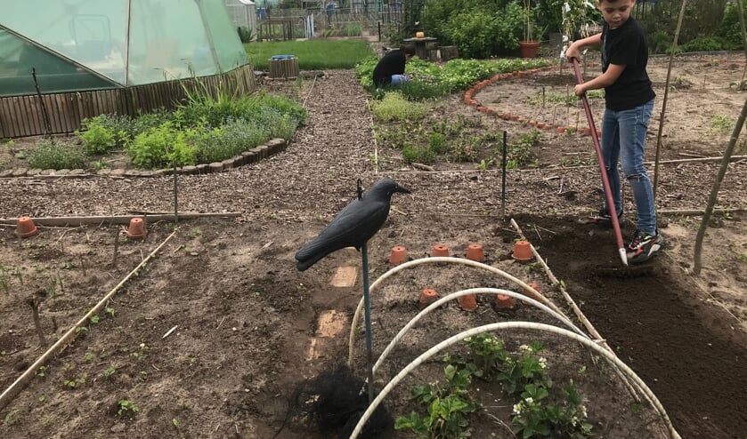 <p>Eén van de kinderen en op de achtergrond een vrijwilliger van Waterkracht enthousiast aan het werk in de tuin. Foto: PR</p>
