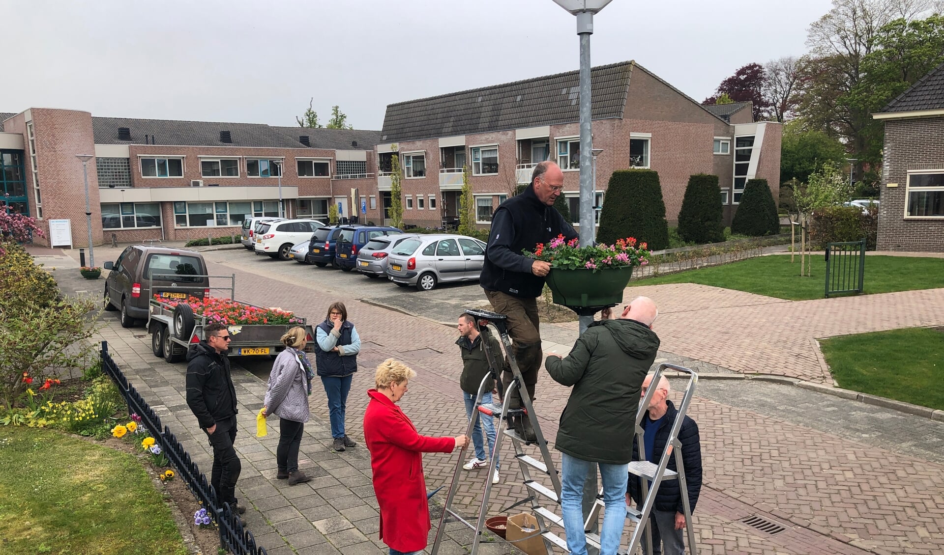 Vrijwilligers gaan de trapjes op om de bloembakken te bevestigen. Foto: Geert Postma