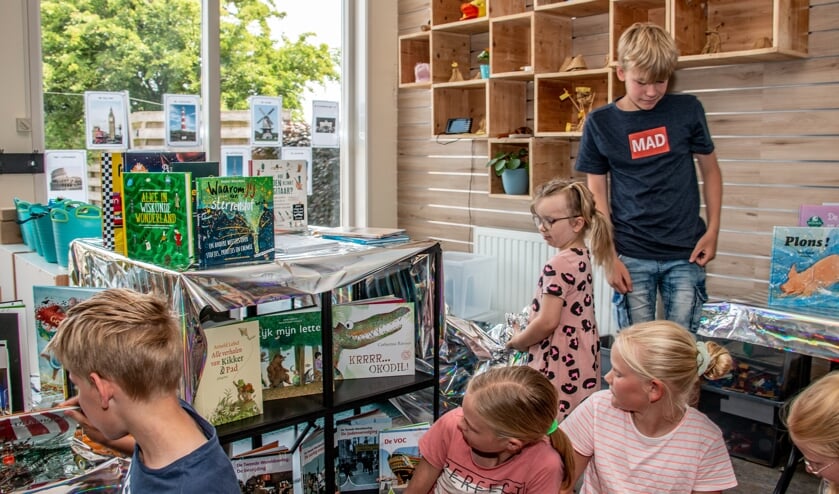 Keano en Anthillia (midden) halen de nieuwe boeken vanonder de folie vandaan. Foto: Liesbeth Spaansen