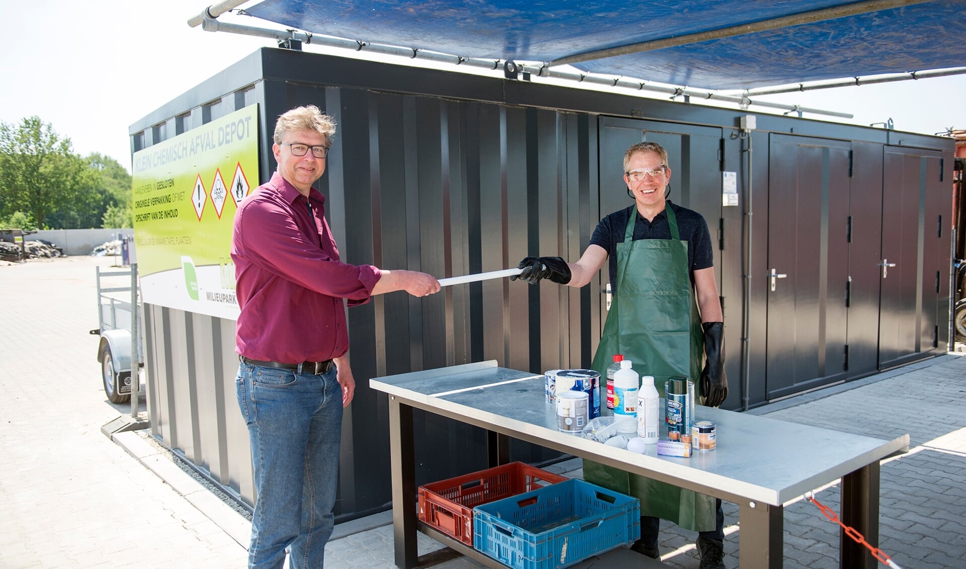 Wethouder Henk van Zeijts (links) opende het innamepunt voor klein chemisch afval op het Recycleplein in Lochem. Medewerker Ronald Colenbrander (rechts) neemt het klein chemisch afval in ontvangst. Foto: Yke Ruessink