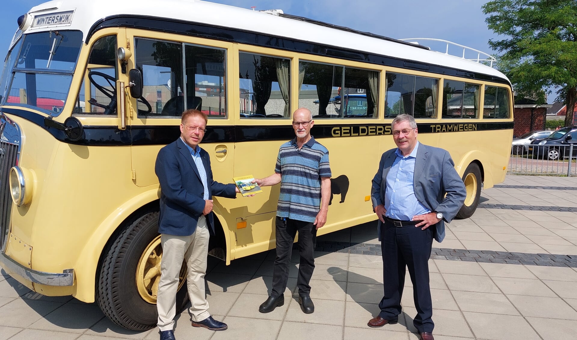 Frank van Setten ziet toe hoe Peter van der Meer (links) aan Henk Beskers het eerste exemplaar van het boek ‘Met de GTW-bus onderweg’ overhandigt. Foto: Han van de Laar