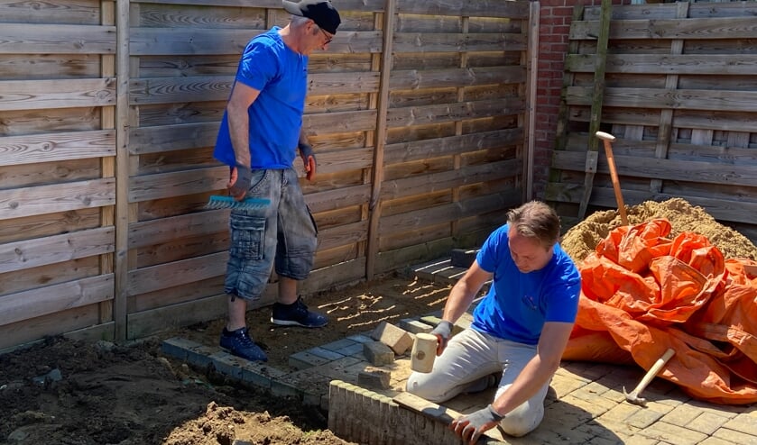 <p>Twee collega's van Iets Anders Makelaars zijn bezig met het afmaken van het terras in de achtertuin. Foto: pr Present Aalten-Dinxperlo </p>