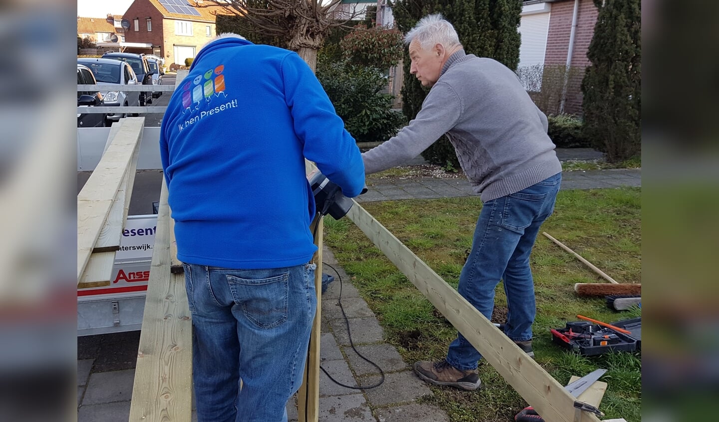 Twee vrijwilligers maken een hek om een voortuin. Foto: Present Winterswijk 