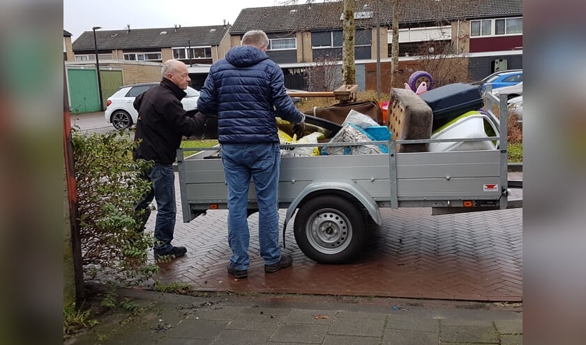 <p>Twee vrijwilligers laden een aanhangwagen vol tijdens een opruimklus. Foto: Present Winterswijk</p>