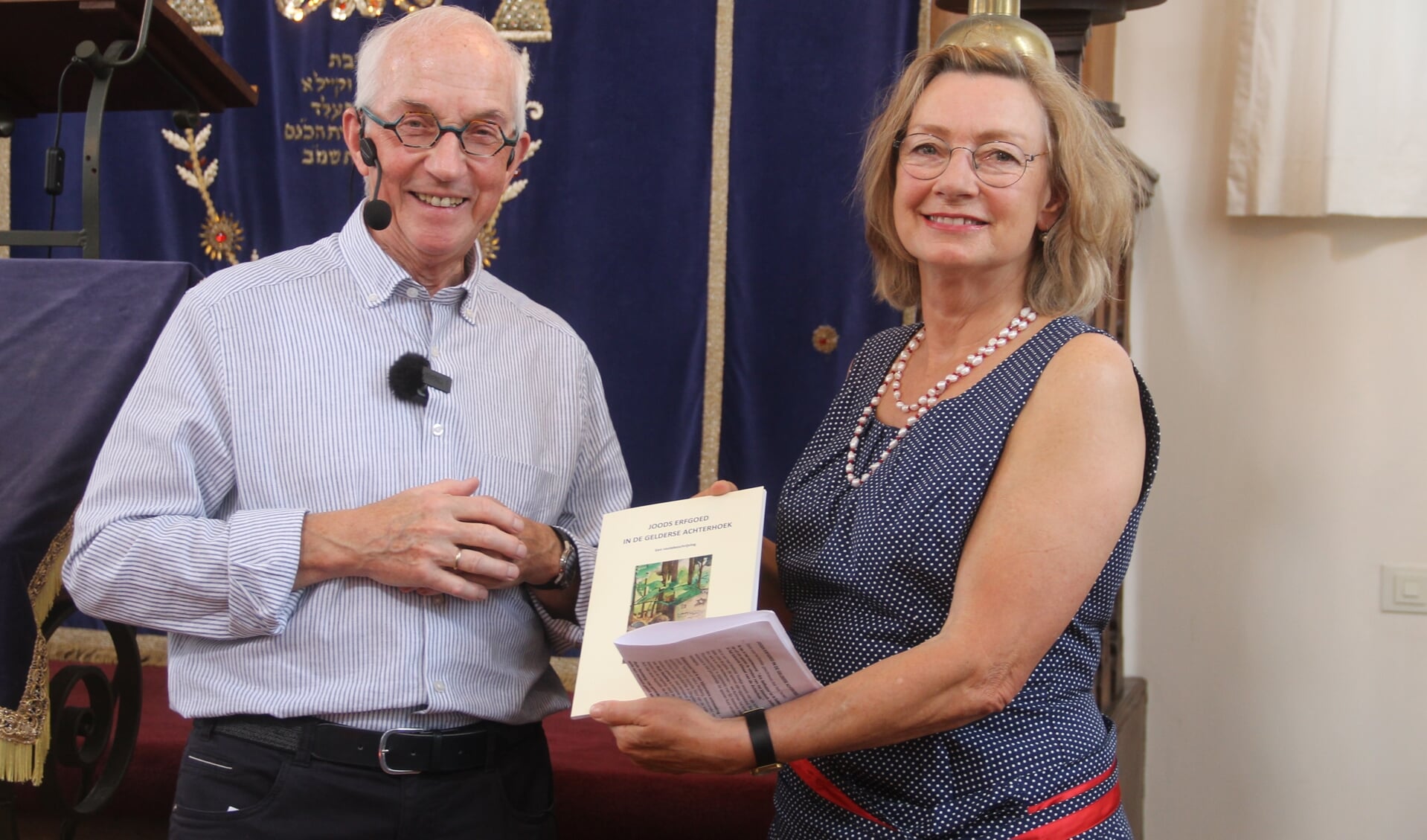 Henk Teeuwen overhandigt het eerste exemplaar van zijn boekje aan Gerda Brethouwer. Foto: Lineke Voltman