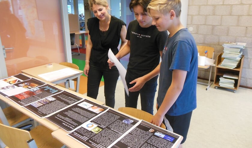 <p>Docent Iris Rozemuller bekijkt met twee leerlingen een van de kranten. Foto: Eric Klop</p>