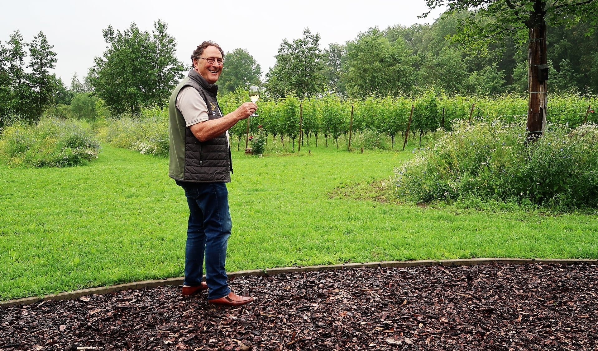 Jules Moormann met een glas wijn van eigen bodem op het buitenverblijf ‘Hof Detharding’ in Harreveld. Foto: Theo Huijskes
