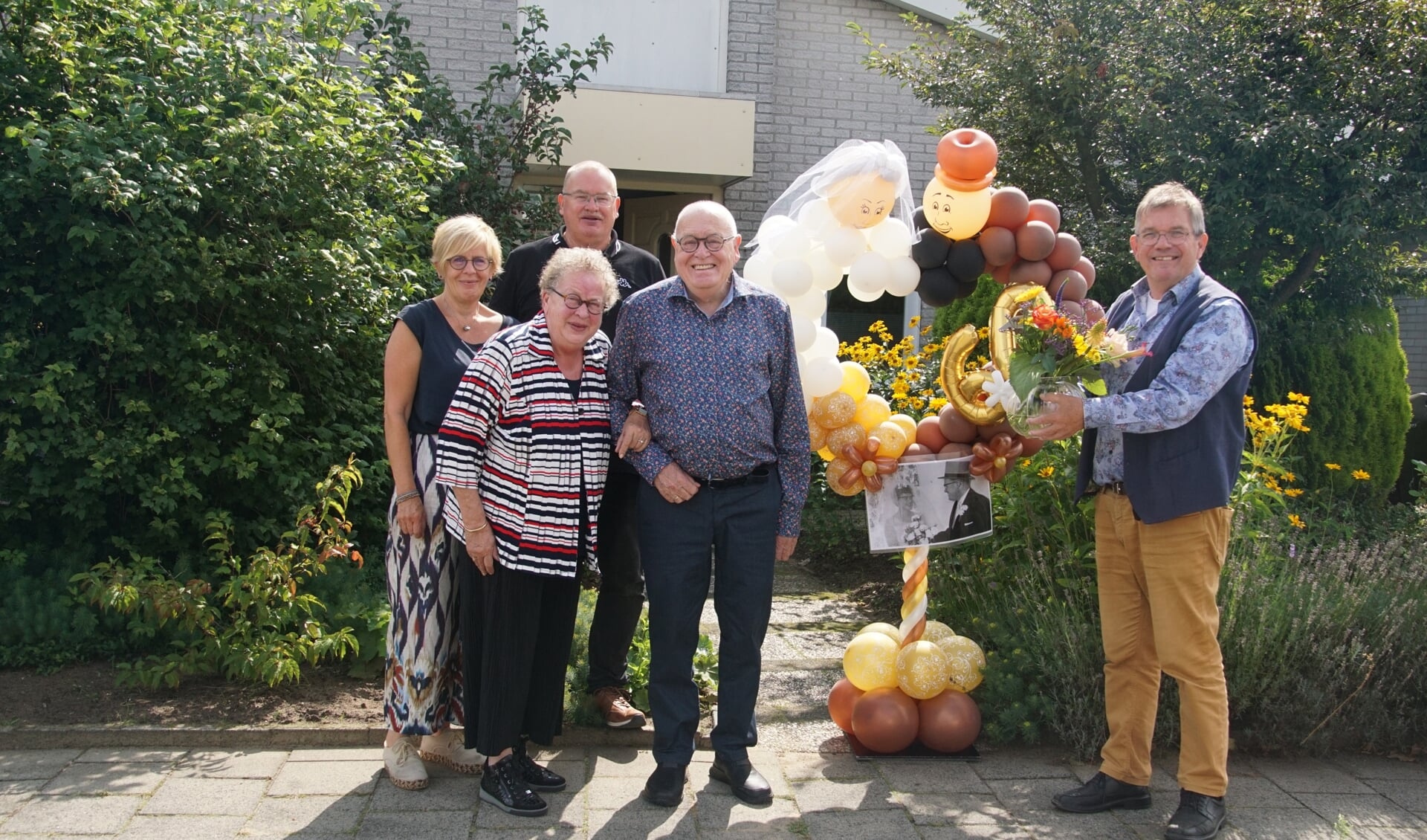 60-jarig echtpaar Herngreen bij de versieringen krijgt bloemen van wethouder Joop Wikkerink. Foto Frank Vinkenvleugel