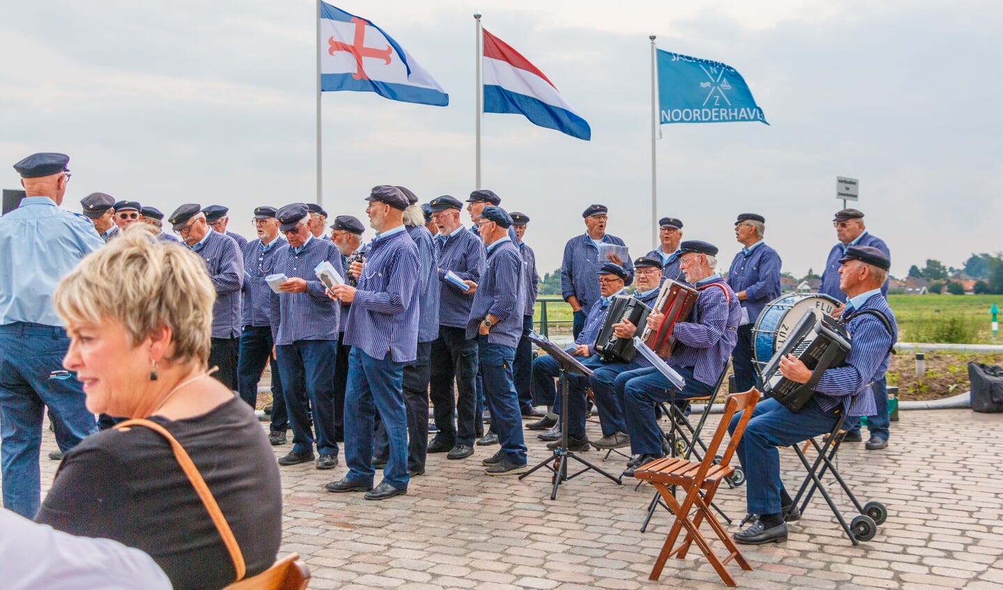 Het koor van de Fluisterbootschippers in actie met daarachter de drie vlaggen. Foto: Henk Derksen