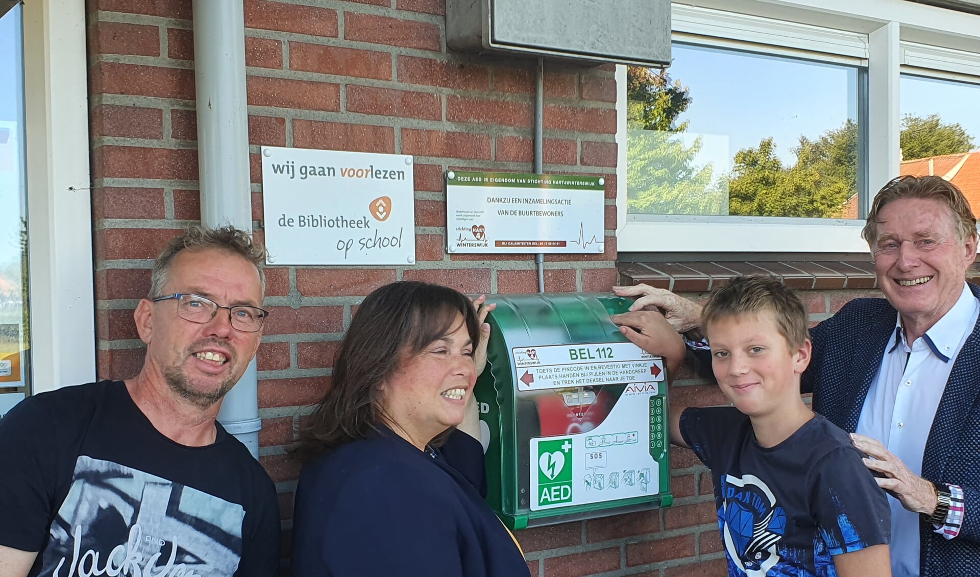 Wethouder Elvira Schepers (links) stelt samen met Bart Jan de buurt-AED in het Woold officieel in werking. Links van haar René Walvoort en uiterst rechts Johan G. Esendam. Foto: PR