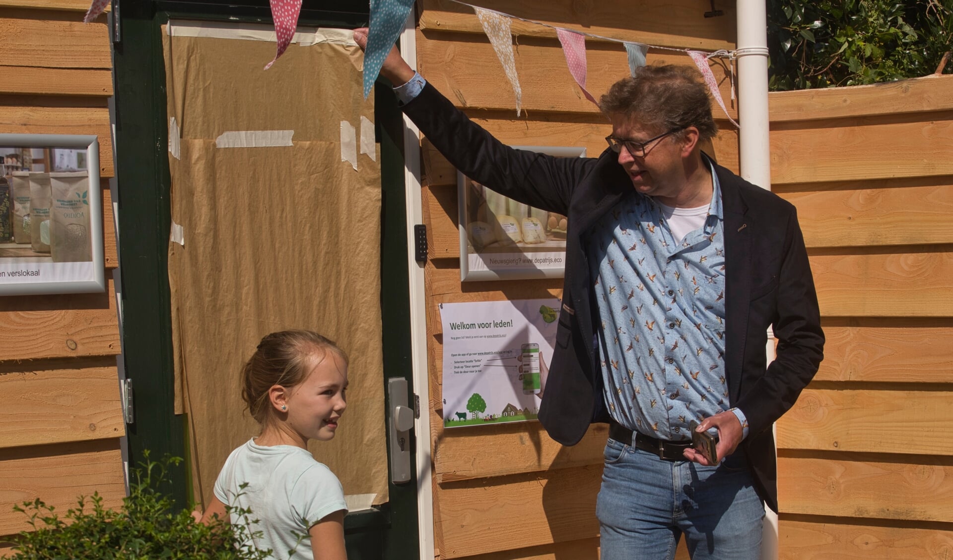 Wethouder Van Zeijts en Yuna Aardeman uit Eefde, een van de winnaars van de kleurwedstrijd, openen het verslokaal in Eefde. Foto: Stefan van Nieuwenhoven/Zutphens Persbureau