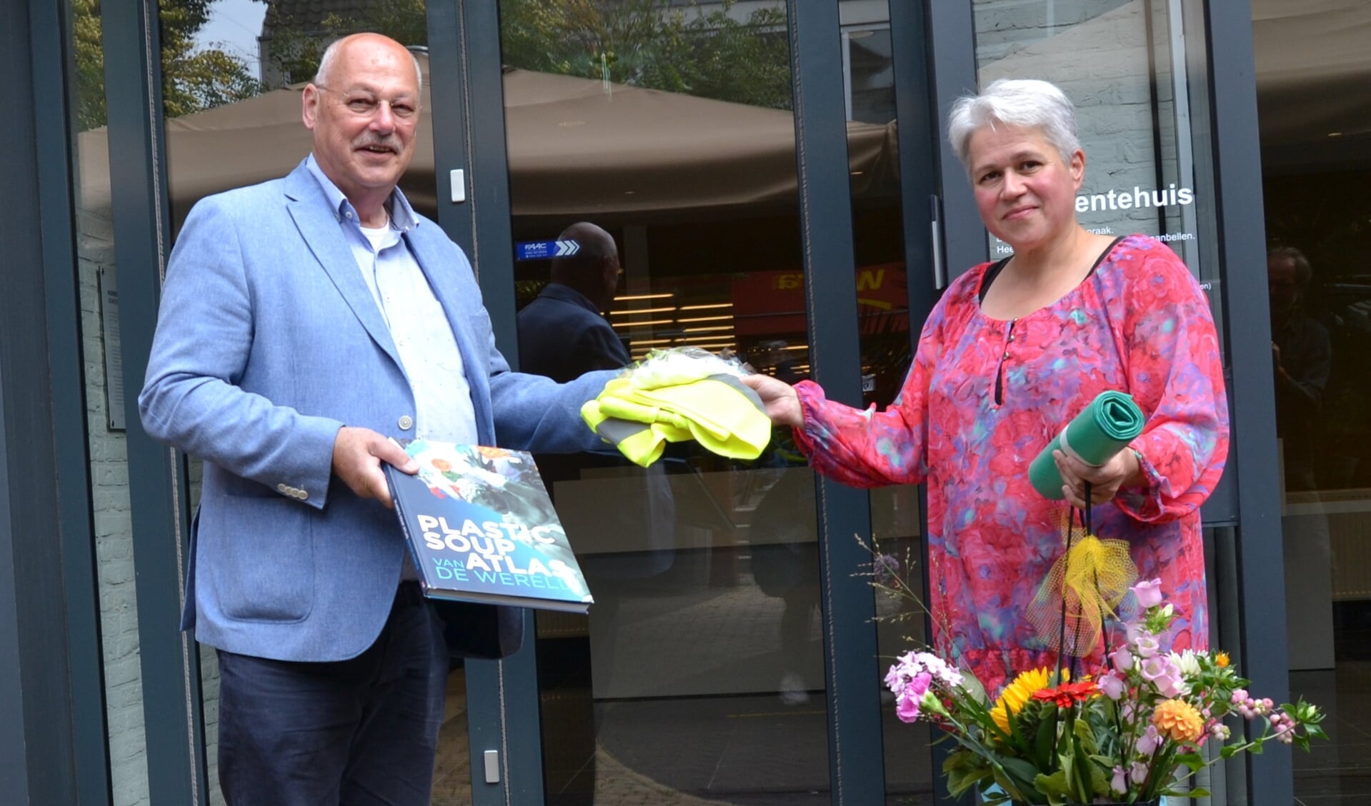 Anke Colenbrander neemt nieuwe hesjes, een boek en bloemen aan van wethouder Martin Veldhuizen. Foto: Karin Stronks