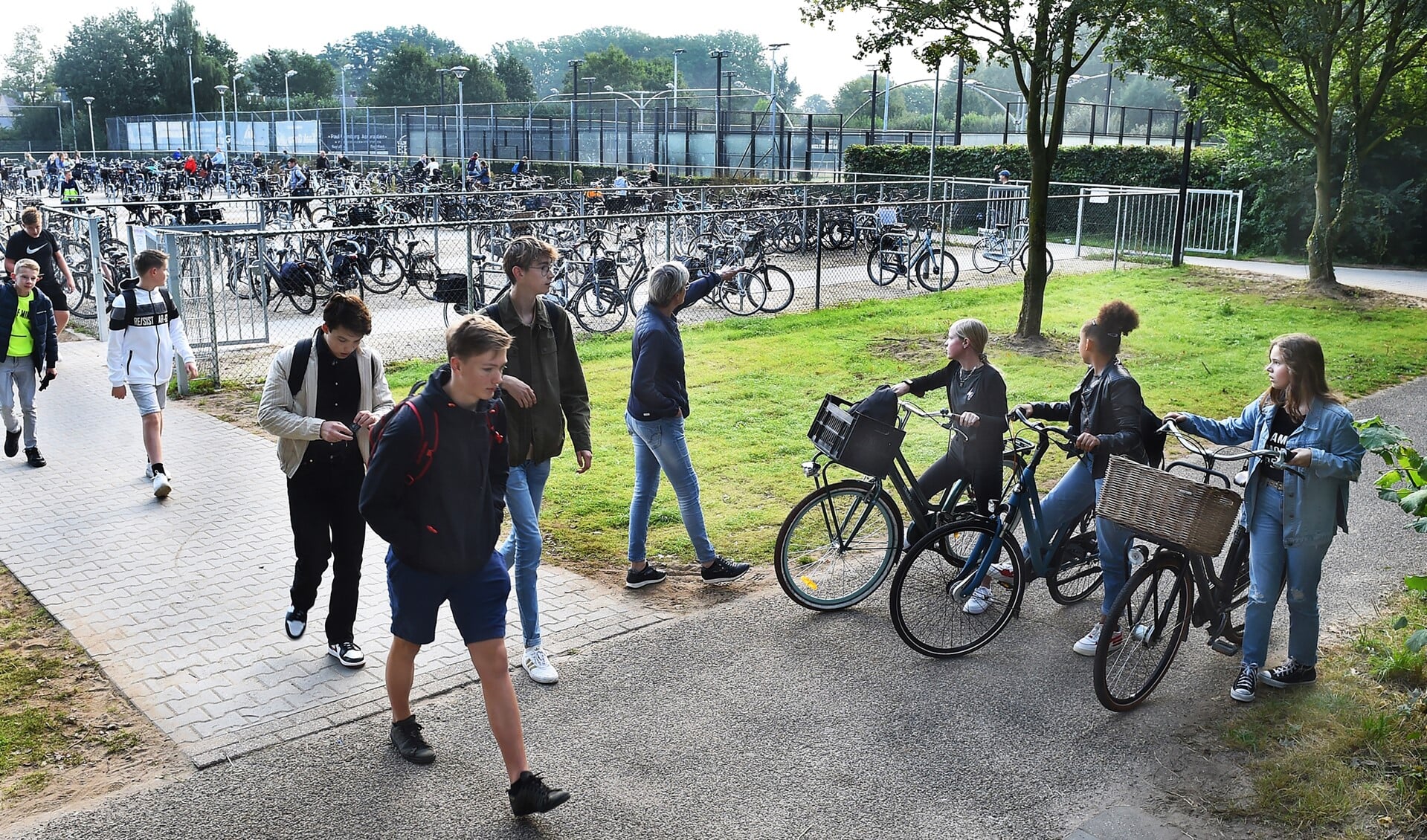 Conciërge Isala Yvonne Mijnen wijst de leerlingen de ingang van de fietsenstalling bij Laudis en Almende College. Foto: Roel Kleinpenning