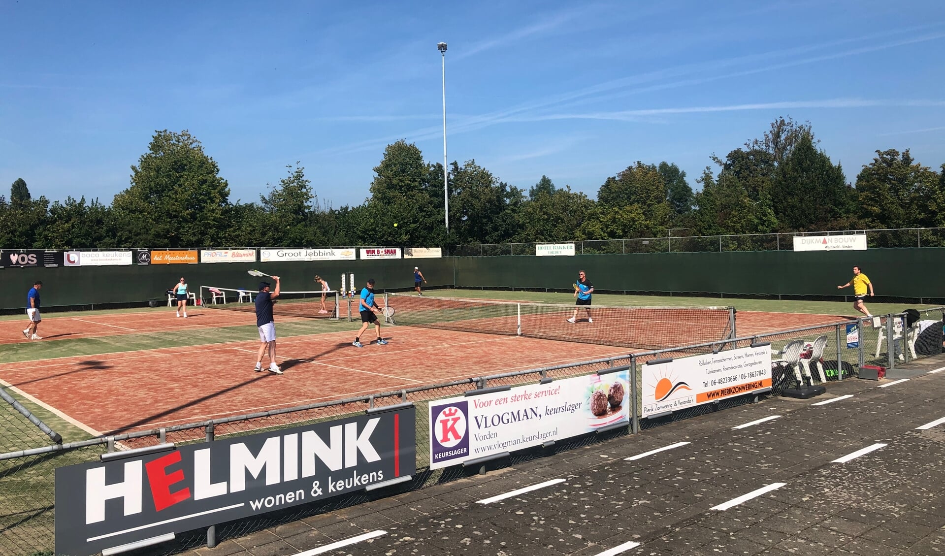 Deelnemers tennistoernooi genieten van zonovergoten weersomstandigheden. Foto: Bas Oonk