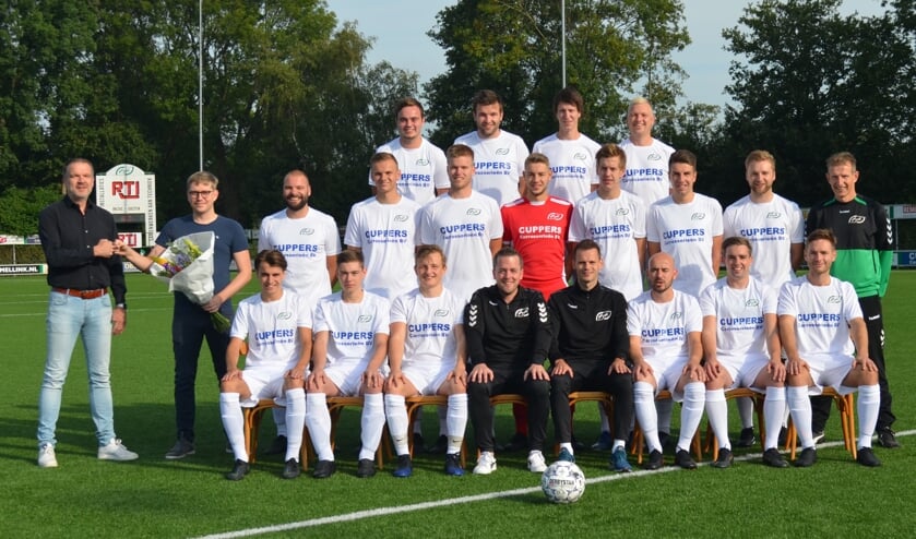 Het tweede team poseert gekleed in de nieuwe tenues enterwijl Joris Wassink van de sponsorcommissie als dank een bos bloemen overhandigt aan David Cuppers van Cuppers Carrosserieën. Foto: PR