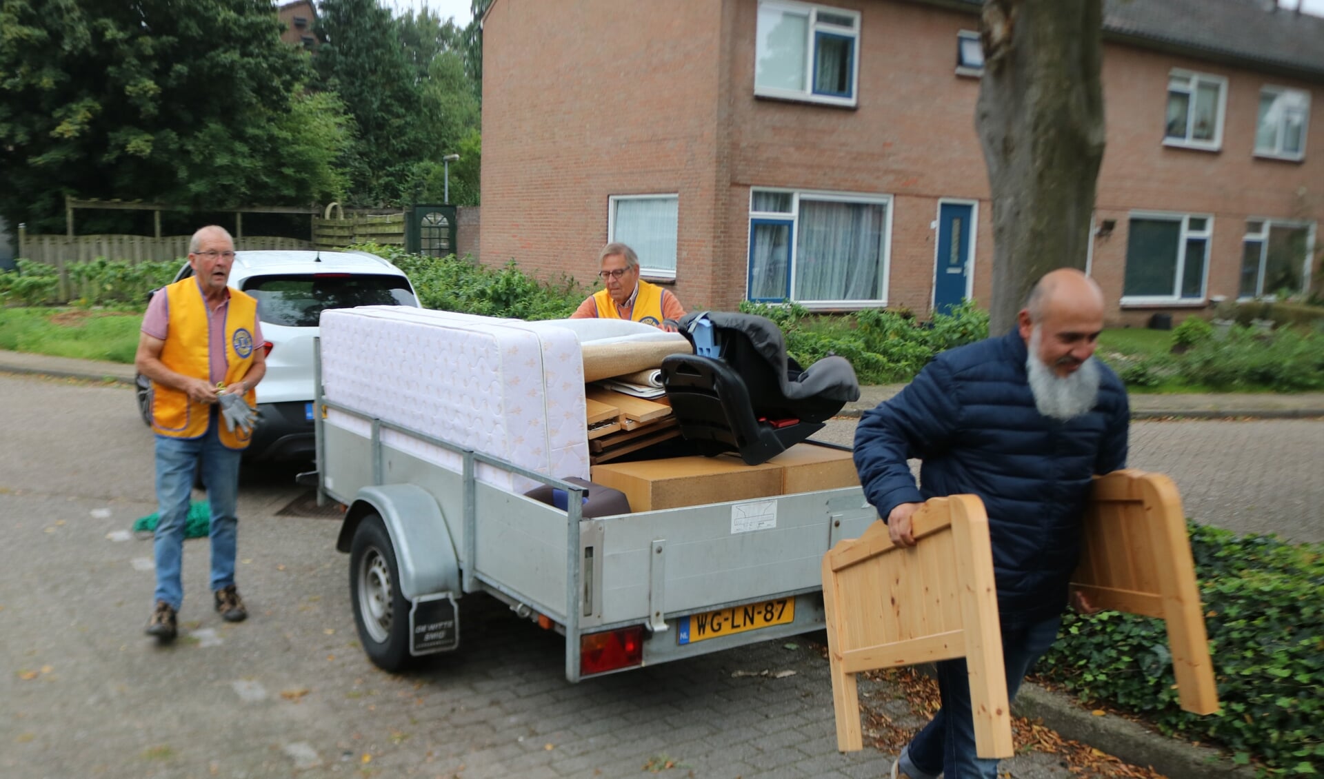 Terwijl Gerrit Harbers, links, en Wiet Burbach de spullen pakken, loop Habib Adli met de kopse kanten van een bed naar zijn huis. Foto: Arjen Dieperink