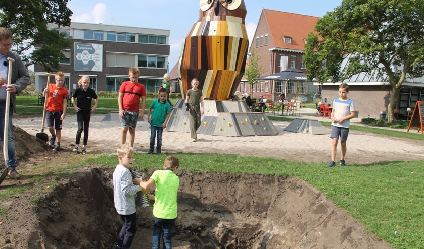 Leerlingen leggen de tijdcapsule in de kuil, die over 50 jaar weer opgegraven wordt. Foto: Lineke Voltman