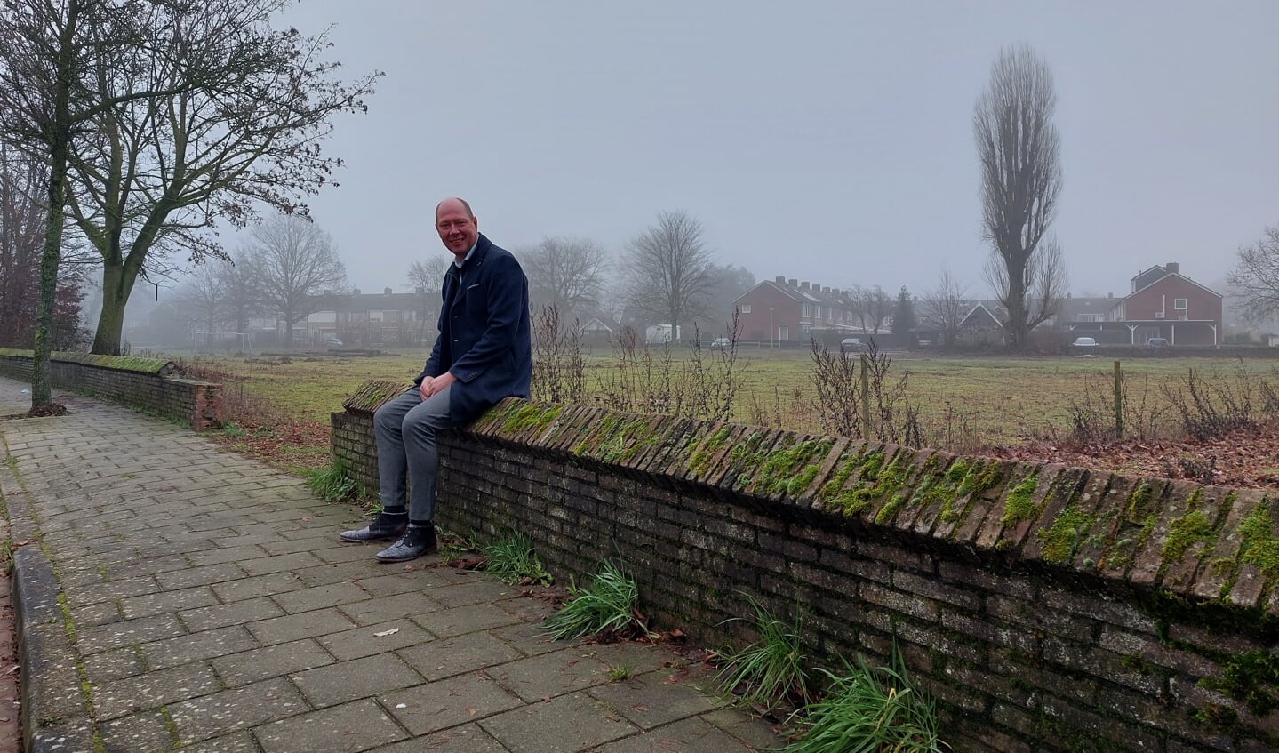Wethouder Kok zit op het karakteristieke muurtje bij bouwlocatie Ludgerstraat. Foto: Karin Stronks