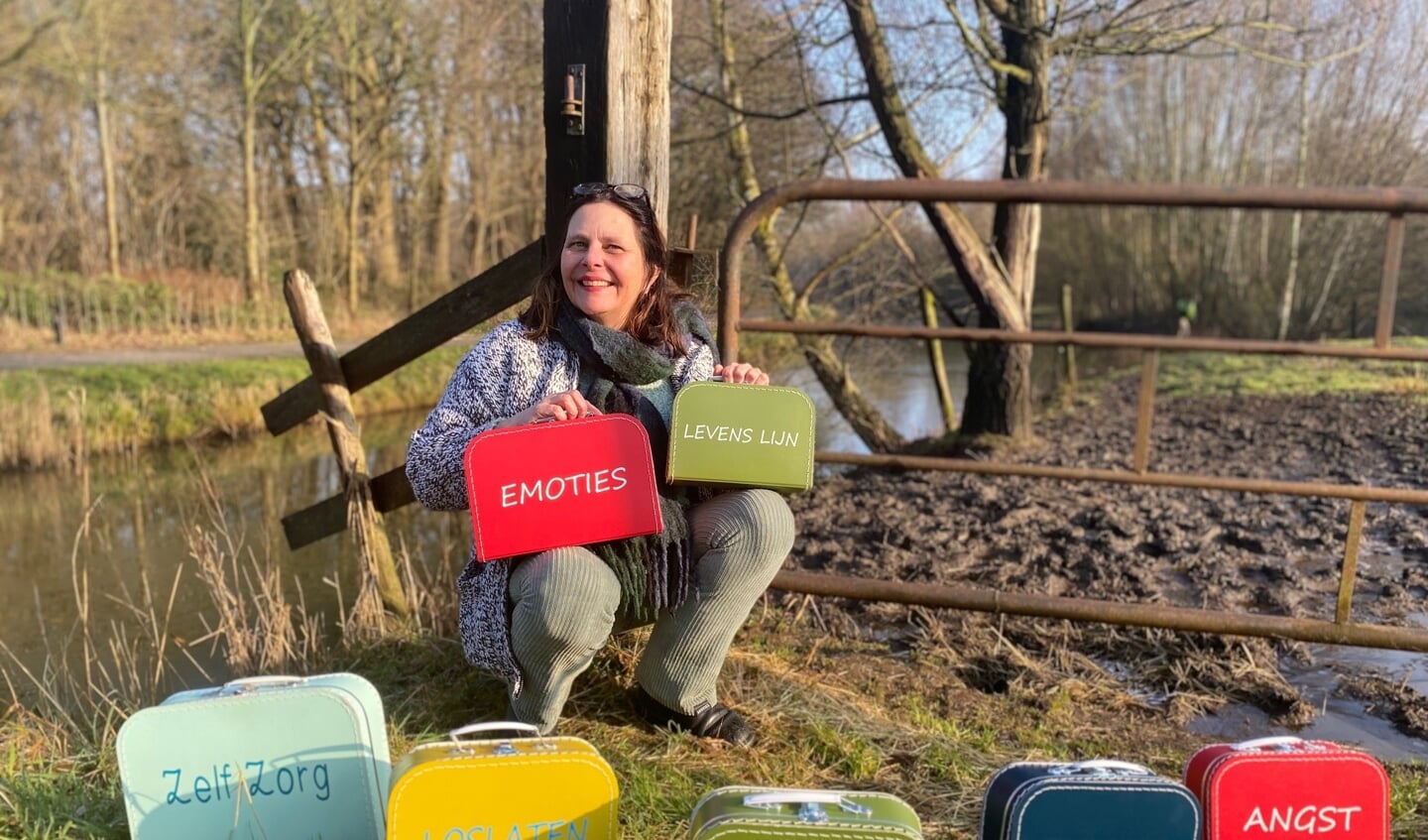 Anoushka Ebbinge te midden van een aantal koffertjes waarin opdrachten zijn verstopt die onder meer jongvolwassenen sterker in hun schoenen doen staan.