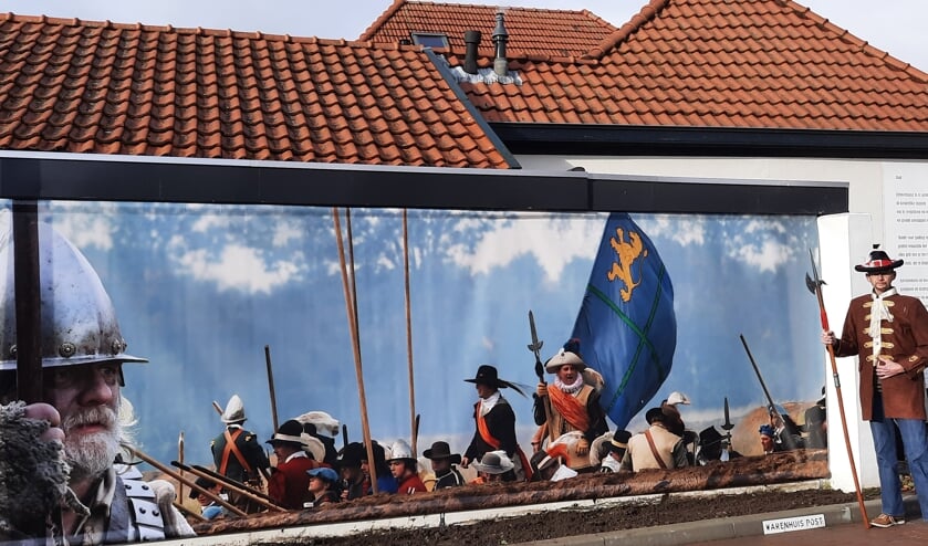 <p>Heino Pelle naast de banner op de muur van zijn woning aan de Rabeldersteeg. Foto: Kyra Broshuis</p>  