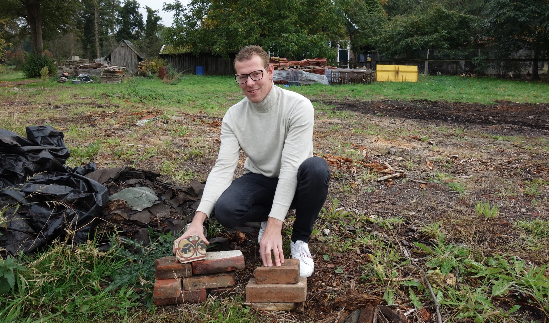 Jos laat een kloostermop en andere stenen zien, die hij goed kan gebruiken. Vanwege het hoopje dakleer en landblouwplastic zou hij al het puin moeten verwijderen op zeer korte termijn. Foto: Clemens Bielen