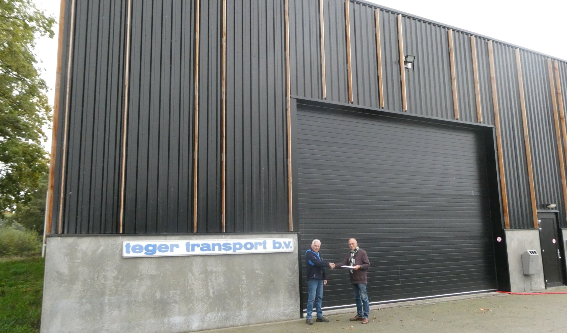 Vorige week zette Henk Teger (r) Appie Broekman bij de bedrijfshal van Teger op het bedrijventerrein De Vente in het zonnetje met een envelop met inhoud. Foto: Jan Hendriksen