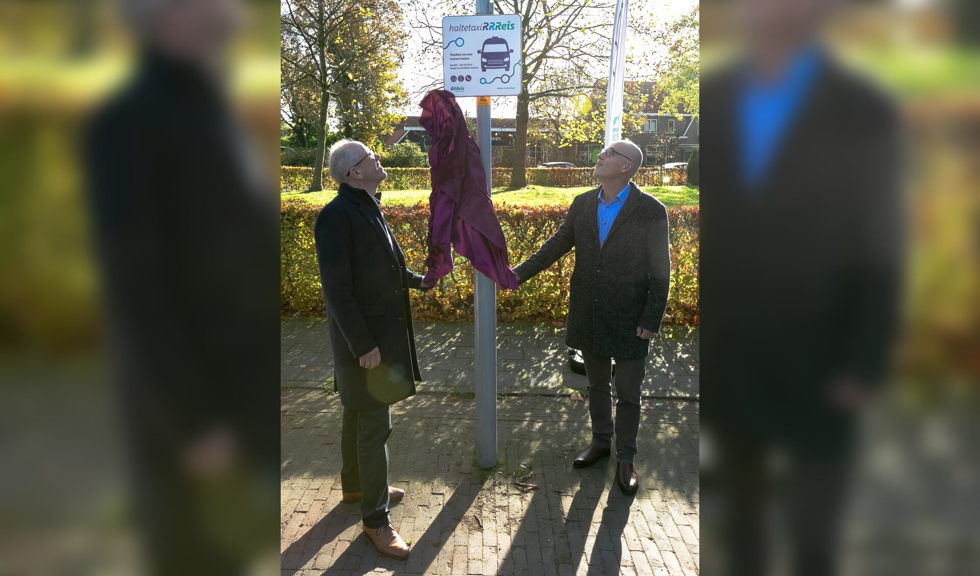 Wethouder Wim Wassink (links) en Paul Pietersen (rechts) onthullen het nieuwe haltetaxi-haltebord in Meddo Winterswijk. Foto: Remco Hesselink
