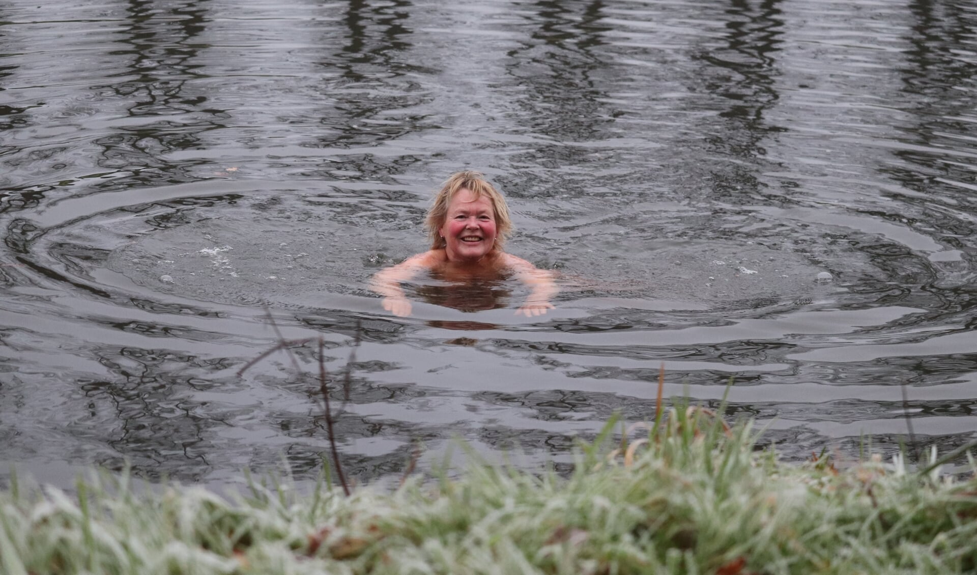 Terwijl het gras aan de oever nog bevroren is, zwemt Edith Meutstege in de Berkel. Foto: Arjen Dieperink