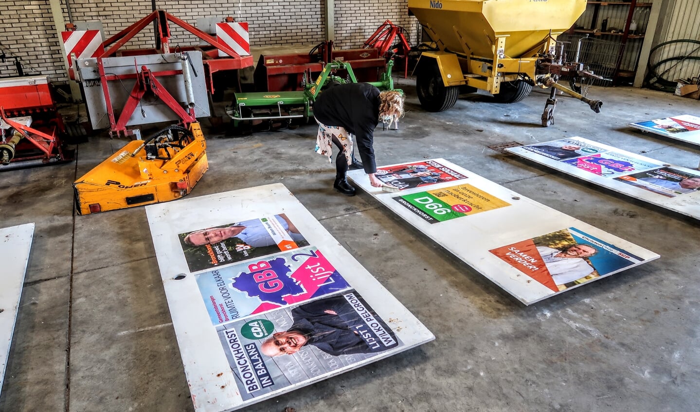 Eén van de leden van de PvdA plakt de poster van haar partij netjes naast die van de andere lokale partijen. Foto: Luuk Stam