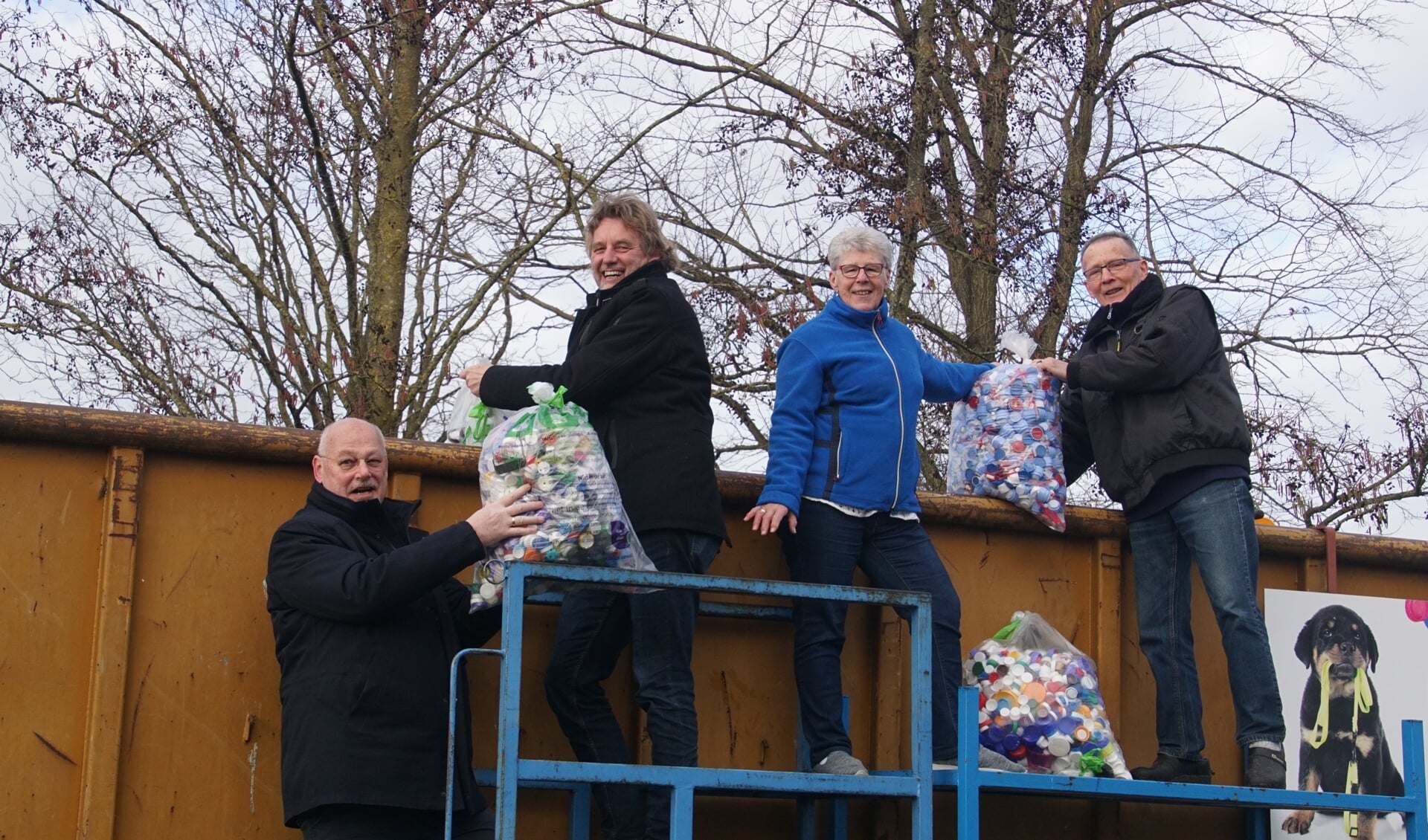 Wethouder Martin Veldhuizen (links), burgemeester Anton Stapelkamp, Annie en Jan Gussinklo gooien zakken vol doppen in de container. Foto: Frank Vinkenvleugel
