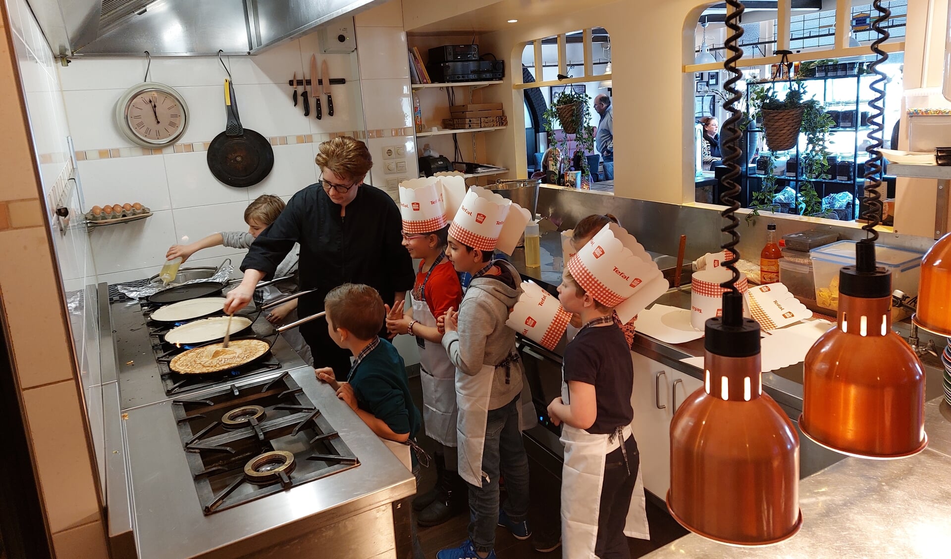 Kinderen met schorten aan en koksmutsen op bakken pannenkoeken. Foto: Karin Stronks