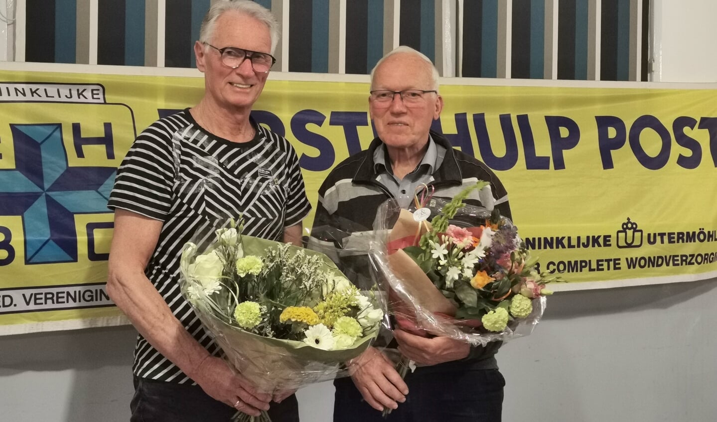 Henk Nijhof (l) en Jan Schepers met hun insigne en de bijbehorende bloemen. Foto: PR. 