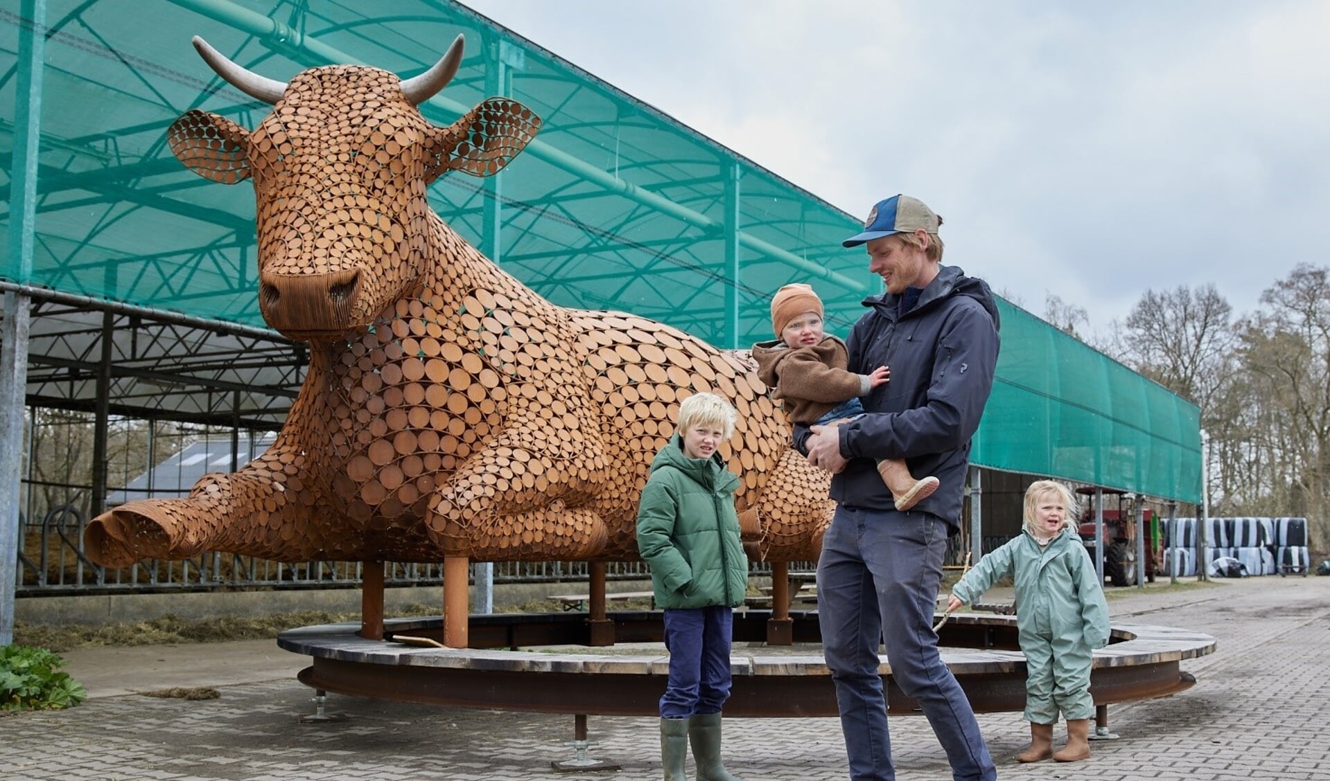 Biodynamische melkveehouder Guus Imhoff met zijn gezin bij 'Ahimsa, de rustende koe' van beeldend kunstenaar Jantien Mook op Urtica de Vijfsprong. Foto: Annelijn Steenbruggen